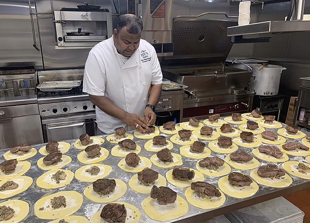 Chef Saku preparing plated beef course at scale